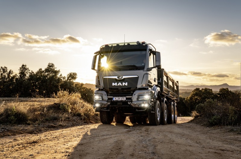 Heavy commercial MAN tipper on a road at sunset